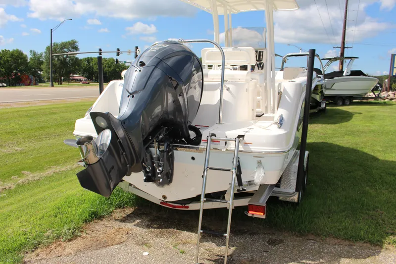 Slide: The Image of 2023 Robalo R222 Center Console boat with outboard motor and ladder on grassy area. - 23