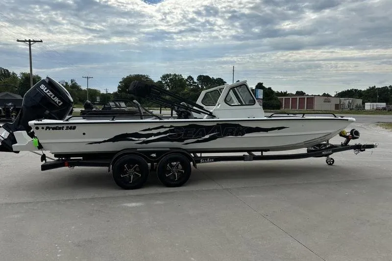 Slide: The Image of 2026 SeaArk ProCat 240 boat on trailer, featuring Suzuki outboard motor, parked outdoors. - 2