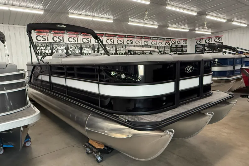 Slide: The Image of 2026 Bentley Pontoons Legacy 243 Navigator in showroom, sleek design, award-winning display. - 2