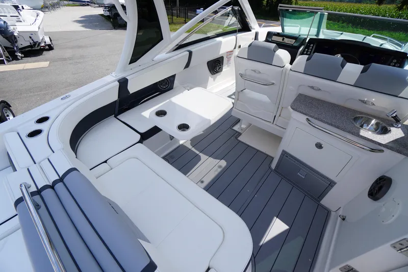 Slide: The Image of 2025 Chaparral 280 OSX boat interior with seating, table, and kitchenette. - 35