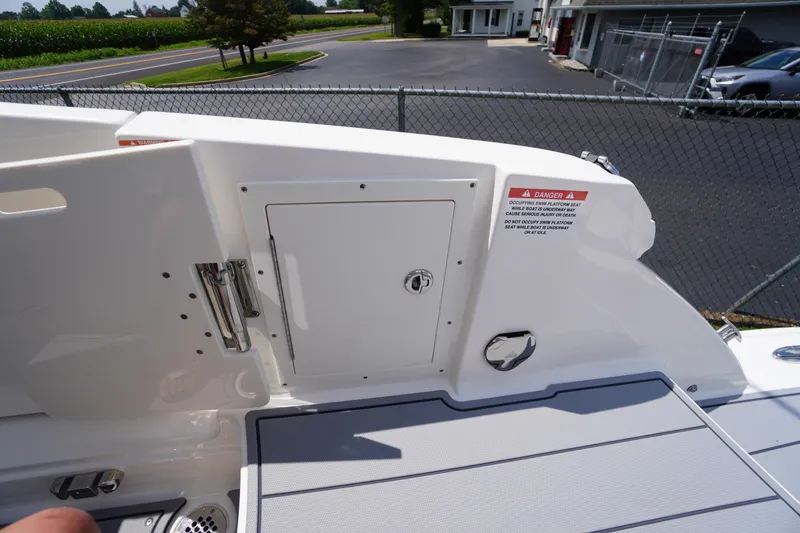 Slide: The Image of 2025 Chaparral 280 OSX boat deck with storage compartment and safety warning label. - 45