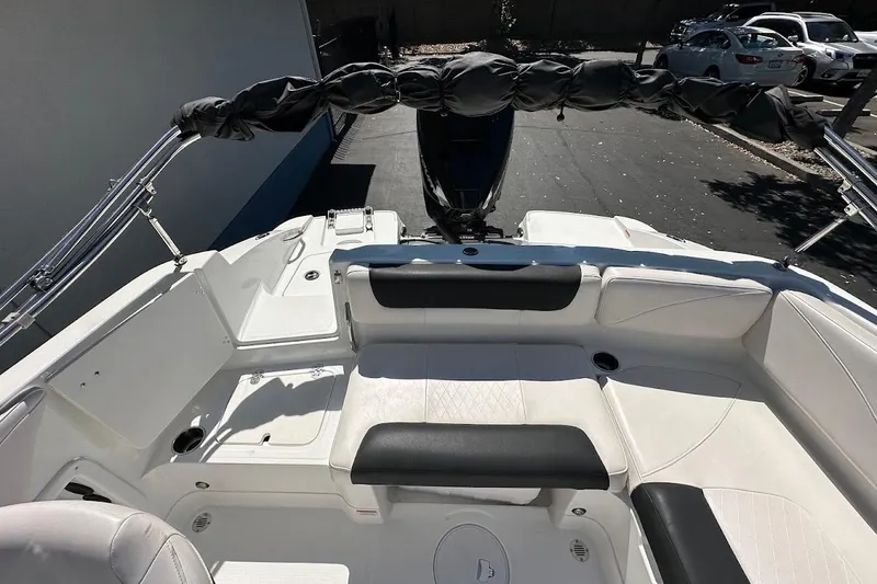 Slide: The Image of 2019 Tahoe 2150 boat interior with white seating and black accents, parked outdoors. - 11