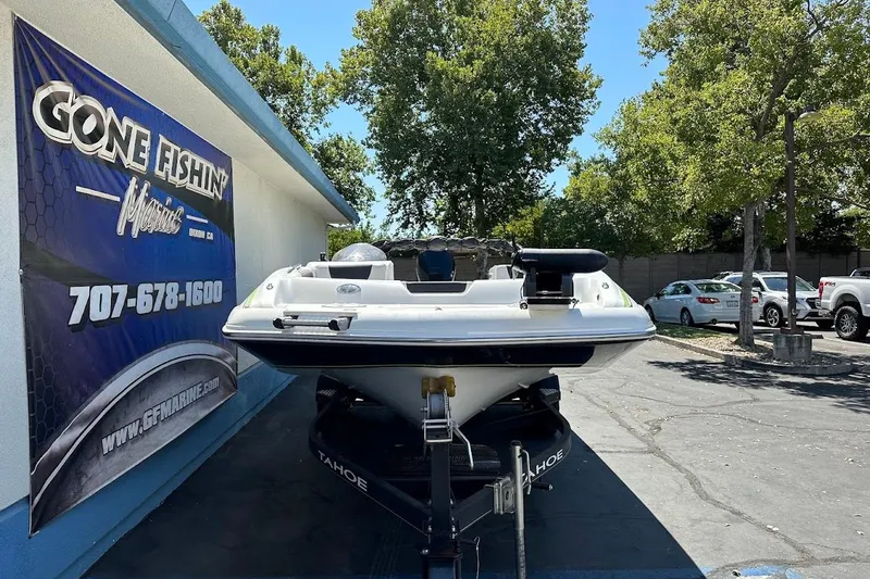 Slide: The Image of 2019 Tahoe 2150 boat on trailer at dealership, surrounded by trees and parked cars. - 3