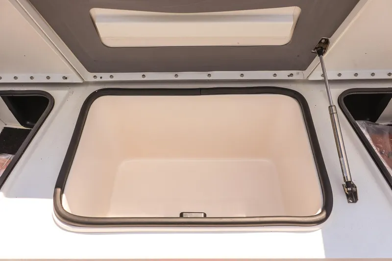 Slide: The Image of Open storage compartment in 2026 Avid 23 Fusion boat, featuring hydraulic support. - 23