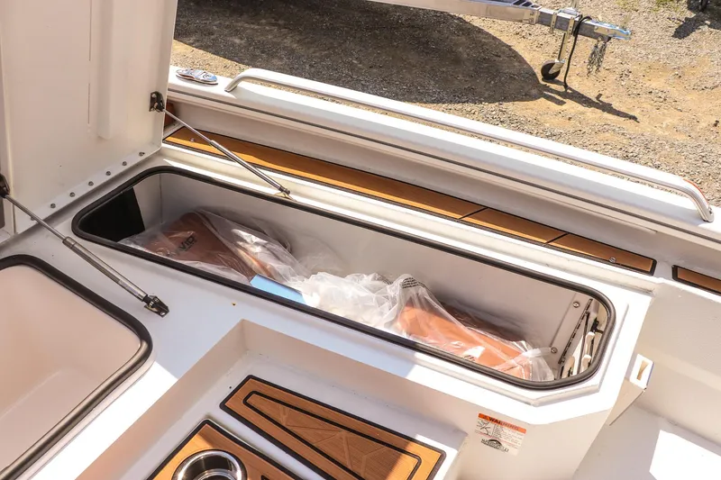 Slide: The Image of Storage compartment on 2026 Avid 23 Fusion boat, featuring wood accents and stainless steel details. - 25