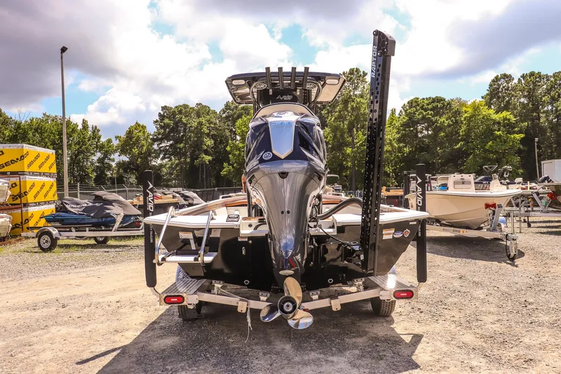 Slide: The Image of 2026 Avid 23 Fusion boat, rear view, parked outdoors with trees and other boats nearby. - 4
