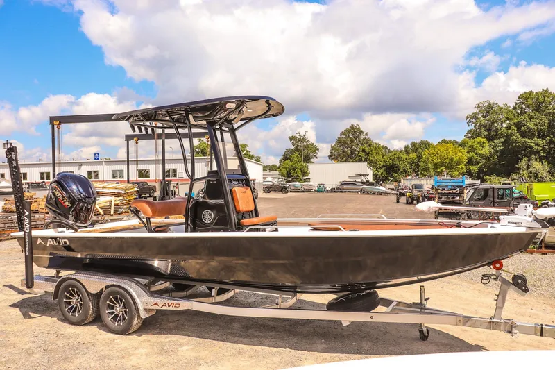 Slide: The Image of 2026 Avid 23 Fusion boat on trailer, parked outdoors under a partly cloudy sky. - 7