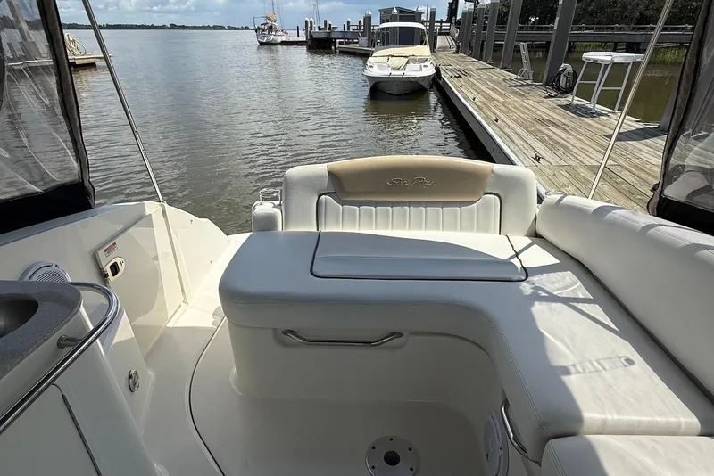 Slide: The Image of 2009 Sea Ray 270 Sundancer boat interior with seating, docked by a wooden pier. - 10