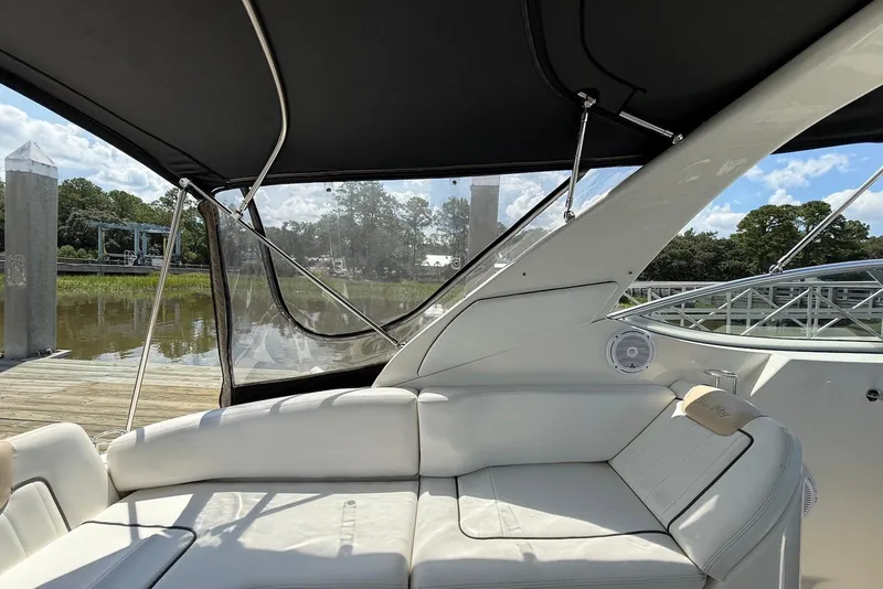 Slide: The Image of 2009 Sea Ray 270 Sundancer interior with white seating and canopy, docked by a serene river. - 14