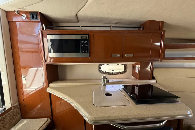 Slide: The Image of 2009 Sea Ray 270 Sundancer interior with kitchenette, featuring microwave, sink, and stove. - 21