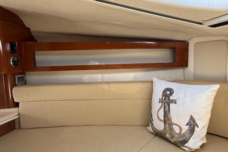 Slide: The Image of Interior of 2009 Sea Ray 270 Sundancer with anchor-themed pillow on beige seating. - 30
