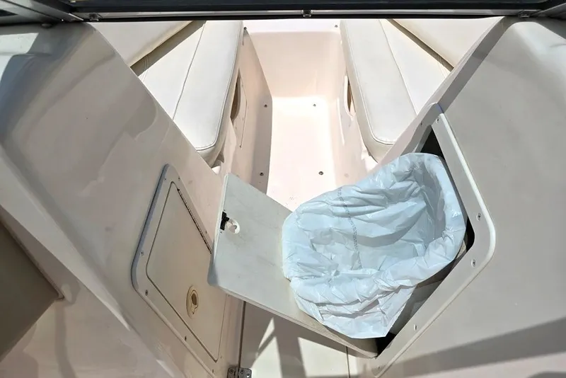 Slide: The Image of 2002 Rinker 212 Captiva BR boat interior with open storage compartment and trash bin. - 15