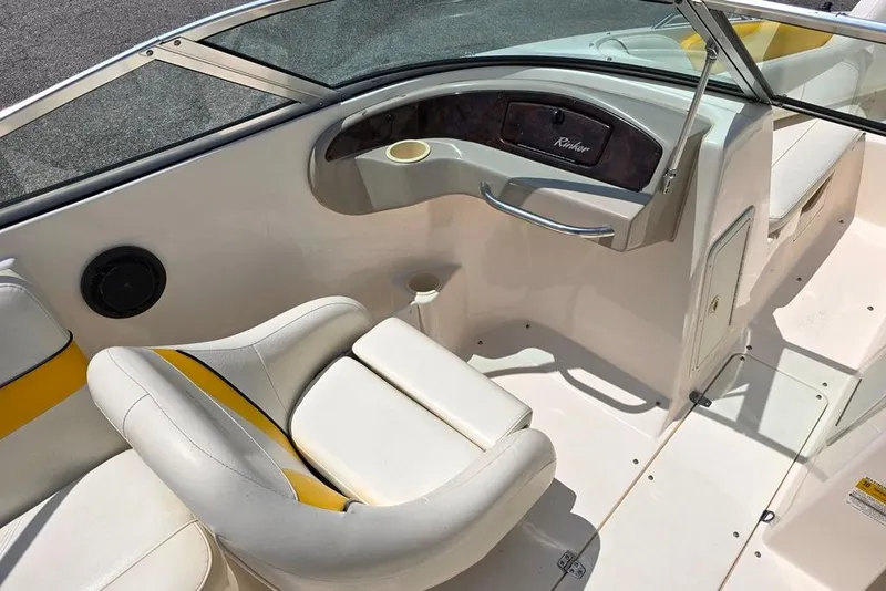Slide: The Image of 2002 Rinker 212 Captiva BR boat interior with white and yellow seating, dashboard, and cup holder. - 4