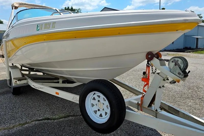 Slide: The Image of 2002 Rinker 212 Captiva BR boat on trailer, featuring yellow and white design. - 7