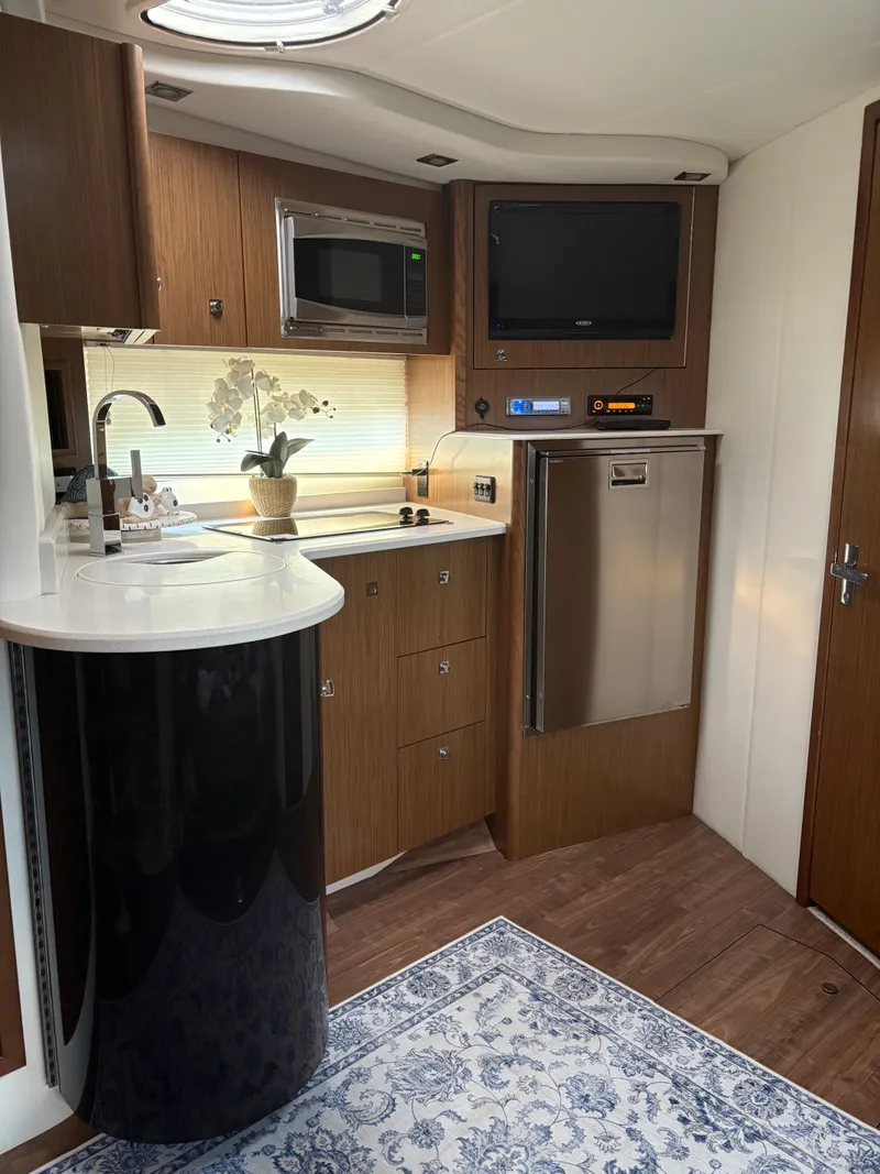 Slide: The Image of 2017 Cruisers Yachts 380 Express interior with kitchenette, microwave, TV, and modern design. - 21