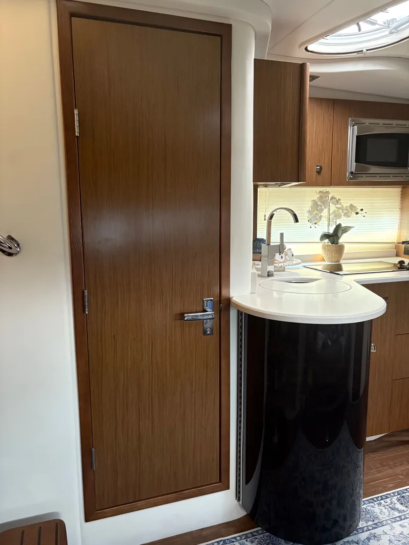 Slide: The Image of Interior of 2017 Cruisers Yachts 380 Express, featuring a sleek kitchenette and wooden door. - 22