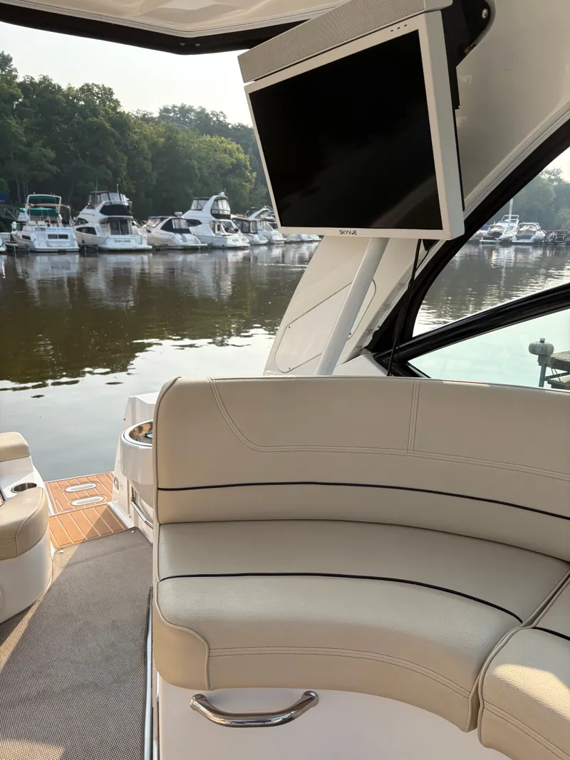 Slide: The Image of 2017 Cruisers Yachts 380 Express interior with seating and TV, docked near other boats. - 9