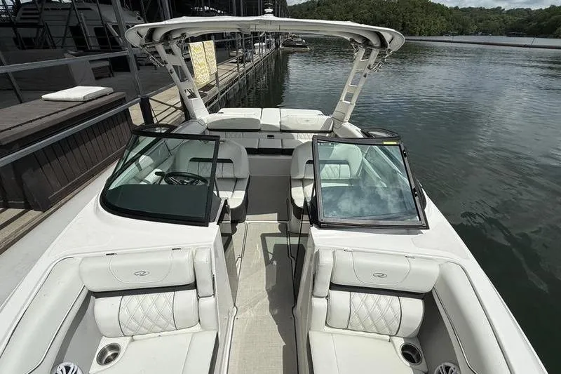 The Image of 2023 Regal LS2 boat interior with white seating, docked by a calm lake. - 1