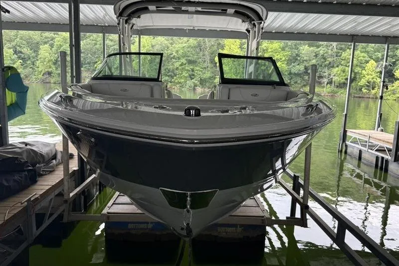 Slide: The Image of 2023 Regal LS2 boat docked in a covered marina with lush greenery background. - 10