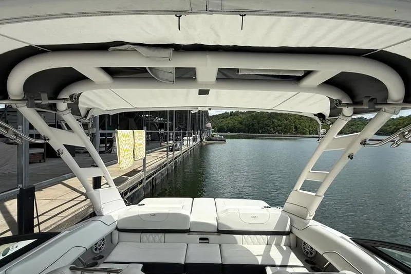 Slide: The Image of 2023 Regal LS2 boat interior with canopy, docked by a serene lake. - 16