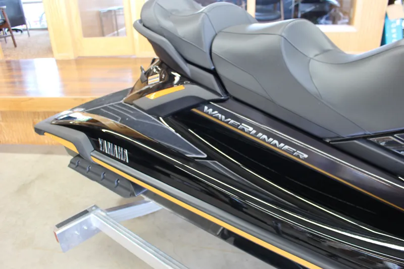 Slide: The Image of 2025 Yamaha FX Cruiser High Output WaveRunner, sleek black design, dual seats, on display indoors. - 5
