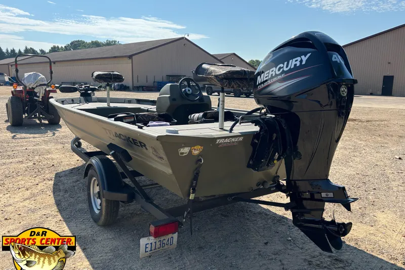 Slide: The Image of 2019 Tracker Grizzly 1754 SC boat with Mercury engine, parked outdoors near a building. - 2