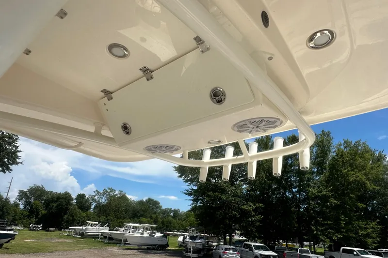 Slide: The Image of 2023 Cobia 262 Center Console boat with rod holders and speakers, parked outdoors. - 17