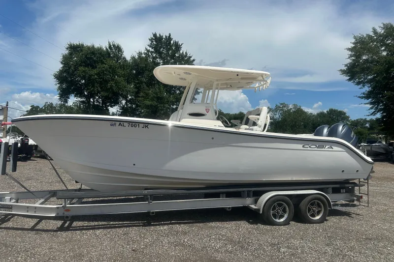 Slide: The Image of 2023 Cobia 262 Center Console boat on trailer, parked outdoors under a clear sky. - 2