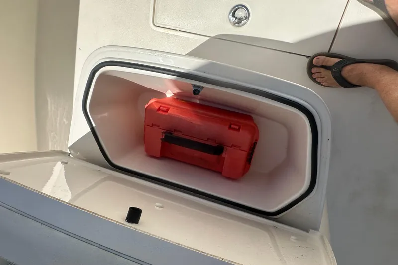 Slide: The Image of Storage compartment on 2023 Cobia 262 Center Console with red toolbox inside. - 21