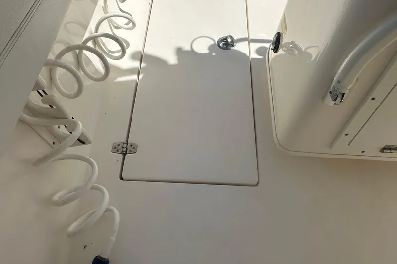 Slide: The Image of 2023 Cobia 262 Center Console deck with coiled hose and storage hatch. - 23