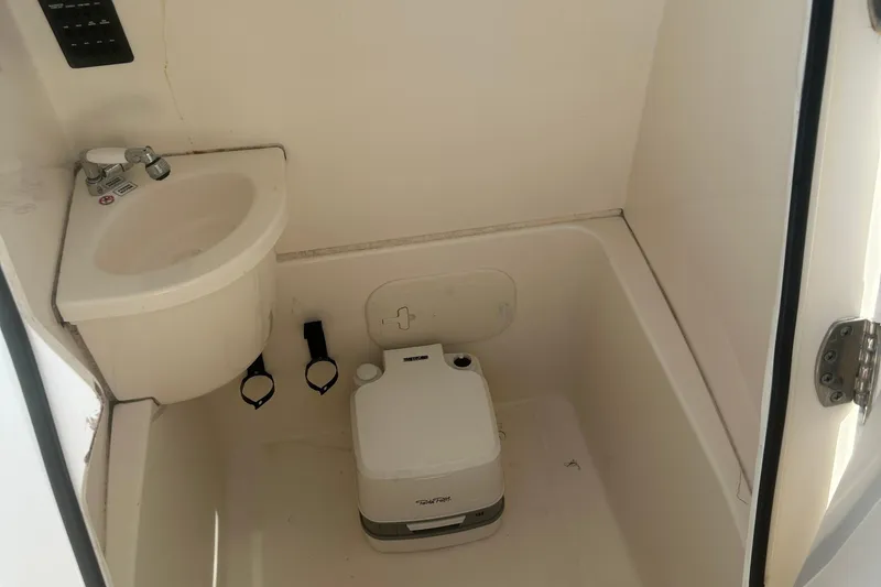 Slide: The Image of 2023 Cobia 262 Center Console boat interior with sink and portable toilet. - 34