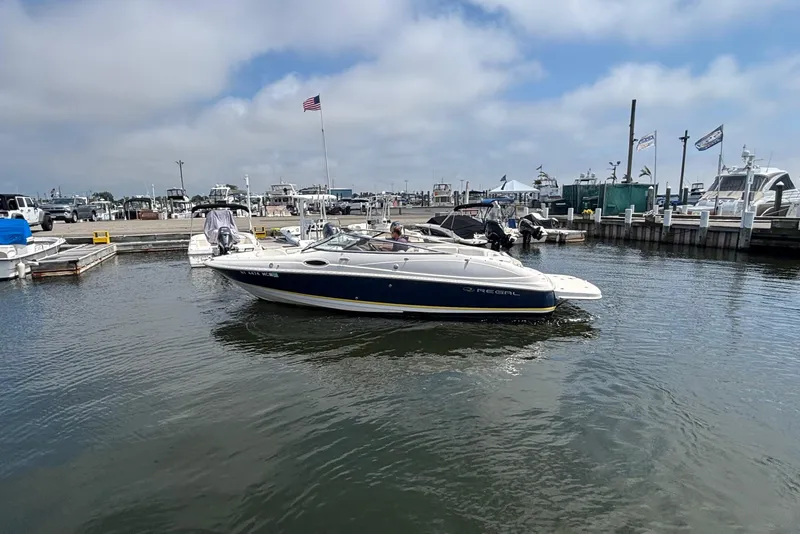 Slide: The Image of 2007 Regal 2400 Bowrider boat docked at a marina under a cloudy sky. - 11
