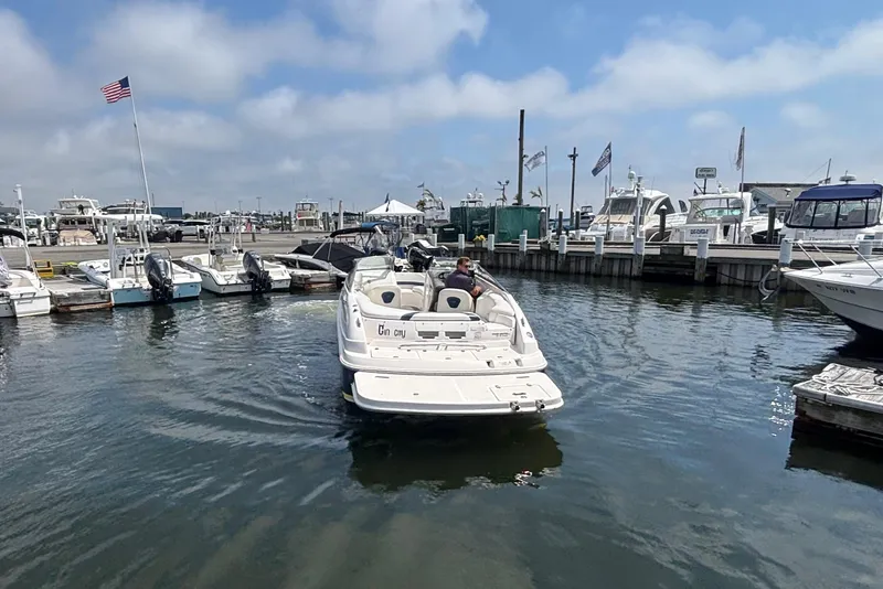 Slide: The Image of 2007 Regal 2400 Bowrider boat navigating marina with docks and American flag. - 13