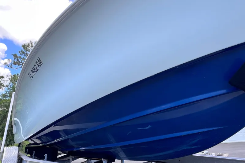 Slide: The Image of 2017 Contender 24 Sport boat with blue hull on trailer, under clear sky. - 10