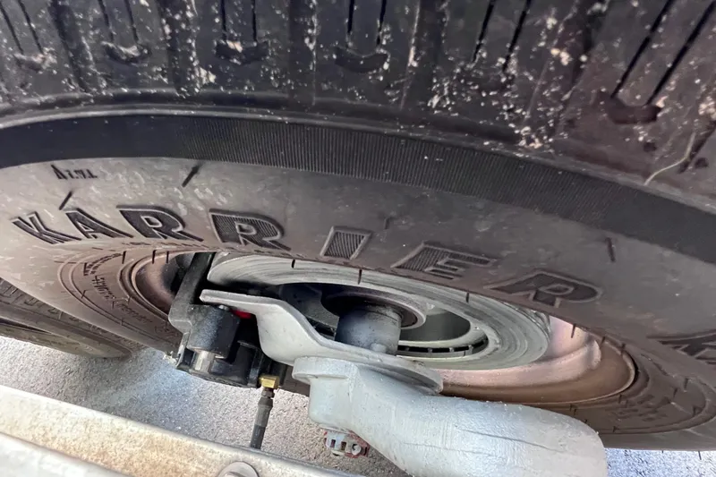 Slide: The Image of Close-up of a 2017 Contender 24 Sport trailer tire with visible suspension components. - 11