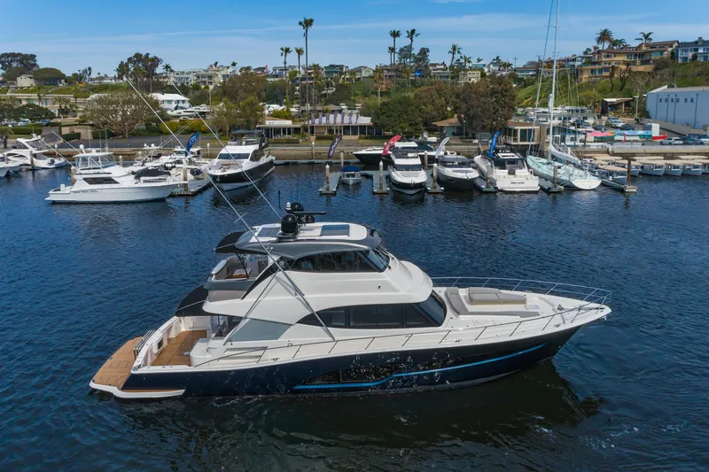 The Image of 2023 Riviera 64 Sports Motor Yacht cruising in urban harbor setting. - 0