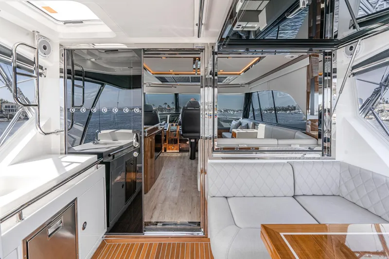 Slide: The Image of Luxurious 2023 Riviera 64 Sports Motor Yacht interior with elegant seating and wooden table. - 16