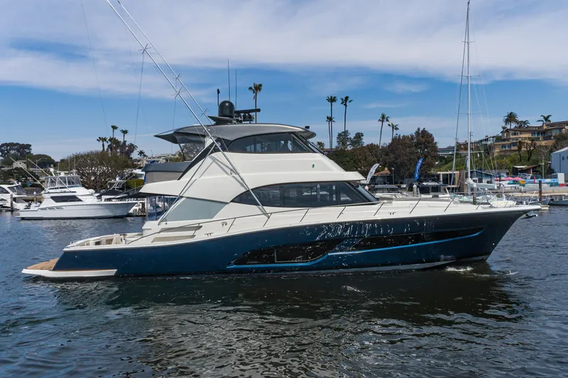 Slide: The Image of 2023 Riviera 64 Sports Motor Yacht cruising near city skyline and historic ships. - 2