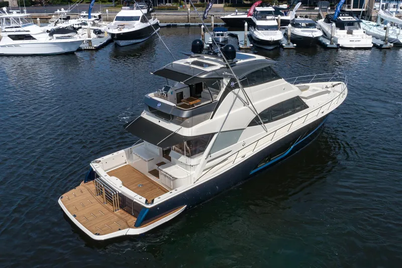 Slide: The Image of 2023 Riviera 64 Sports Motor Yacht cruising in a scenic harbor setting. - 3