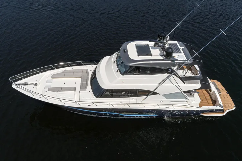 Slide: The Image of 2023 Riviera 64 Sports Motor Yacht with tender on deck, docked on calm water. - 7