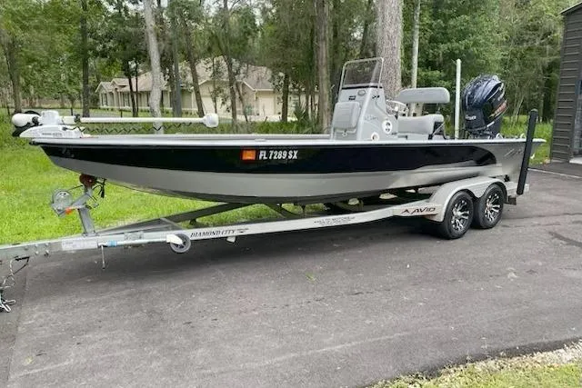 The Image of 2021 Avid 23 FS Magnum boat on trailer, parked outdoors near trees. - 0