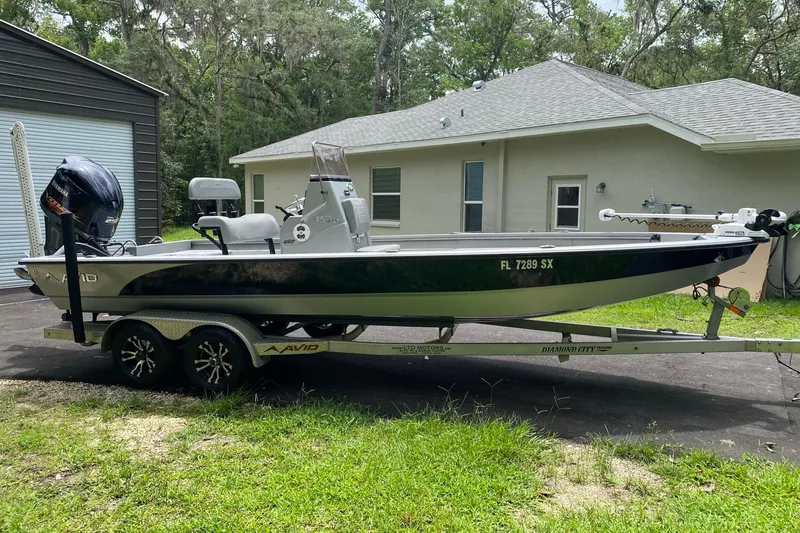 Slide: The Image of 2021 Avid 23 FS Magnum boat on trailer, parked beside a house. - 1