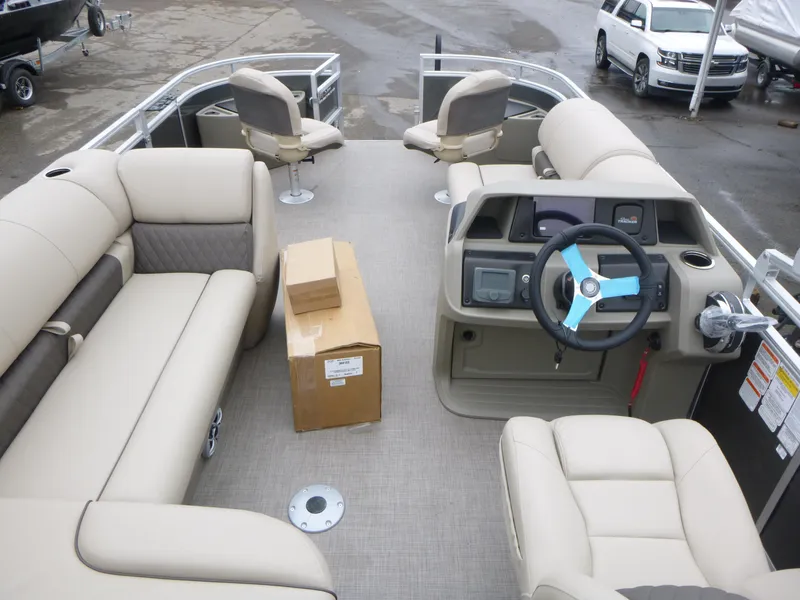 Slide: The Image of 2025 Sun Tracker Fishin' Barge 20 DLX interior with beige seating and steering console. - 14