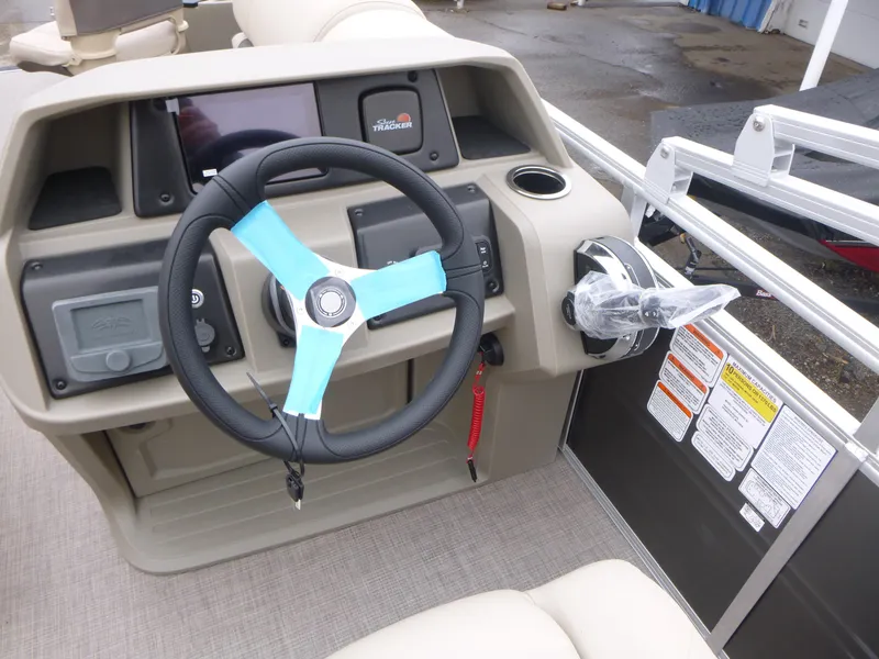Slide: The Image of 2025 Sun Tracker Fishin' Barge 20 DLX steering console with modern controls and blue-accented wheel. - 15