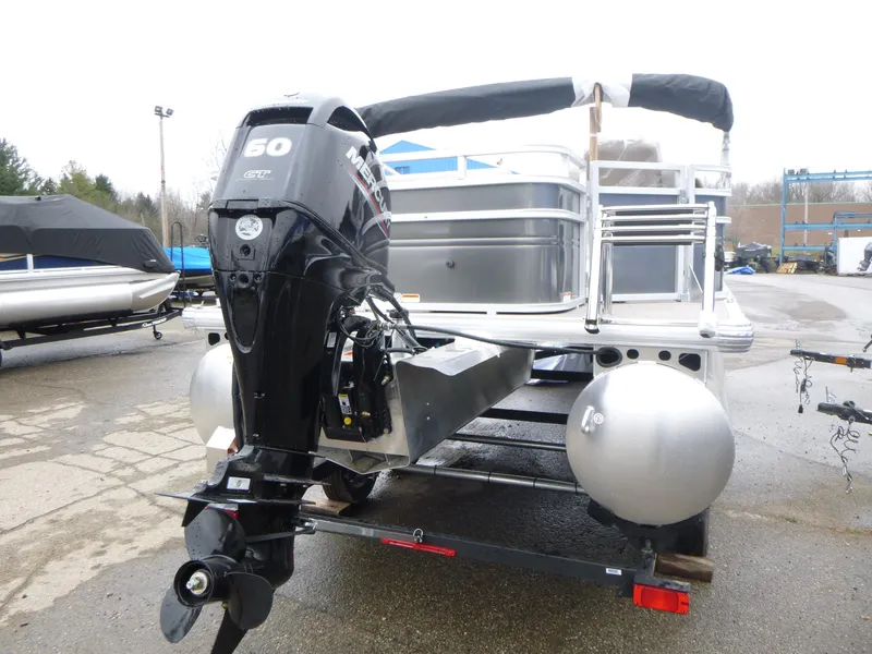 Slide: The Image of 2025 Sun Tracker Fishin' Barge 20 DLX pontoon boat with outboard motor, parked outdoors. - 3