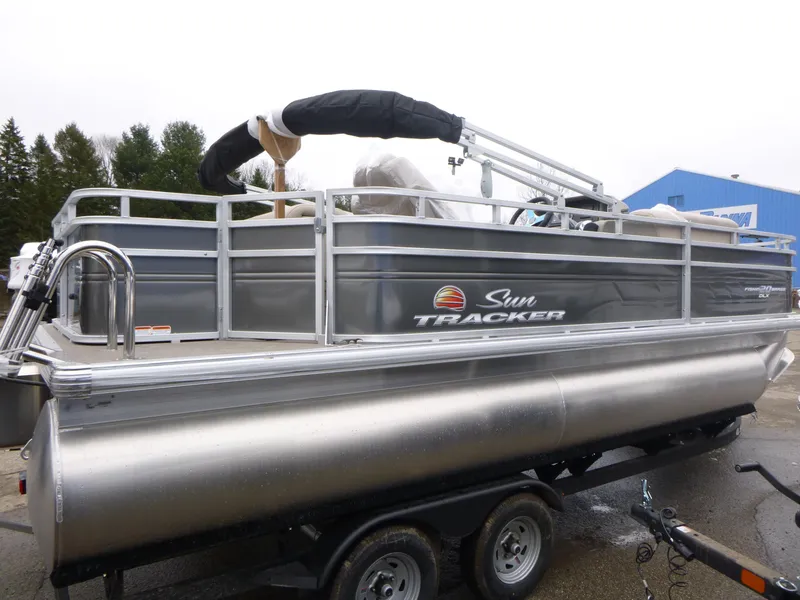 Slide: The Image of 2025 Sun Tracker Fishin' Barge 20 DLX pontoon boat on trailer, side view. - 5