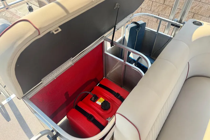 Slide: The Image of Open storage compartment in 2016 Apex Qwest 7518 LS boat with red fuel tank. - 18
