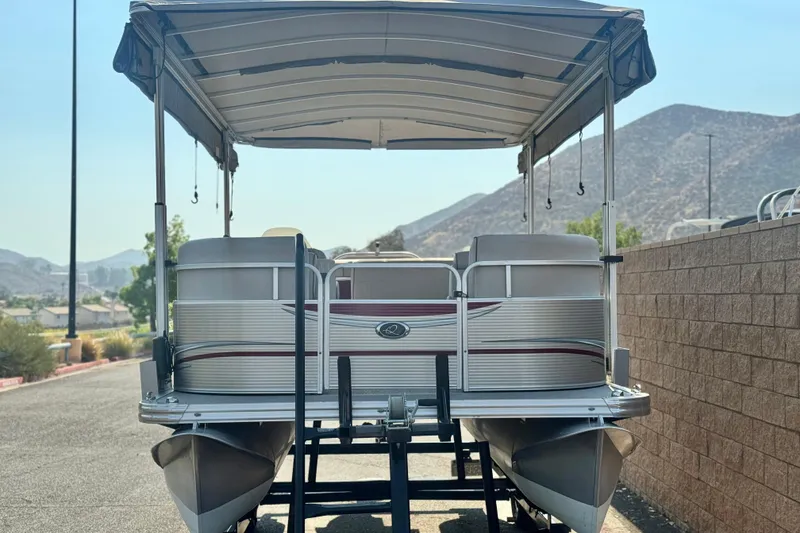 Slide: The Image of 2016 Apex Qwest 7518 LS pontoon boat on trailer, mountain backdrop. - 2