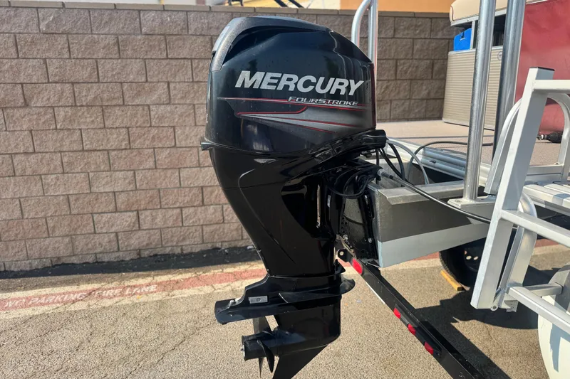Slide: The Image of 2016 Apex Qwest 7518 LS with Mercury FourStroke outboard motor, parked by a brick wall. - 7