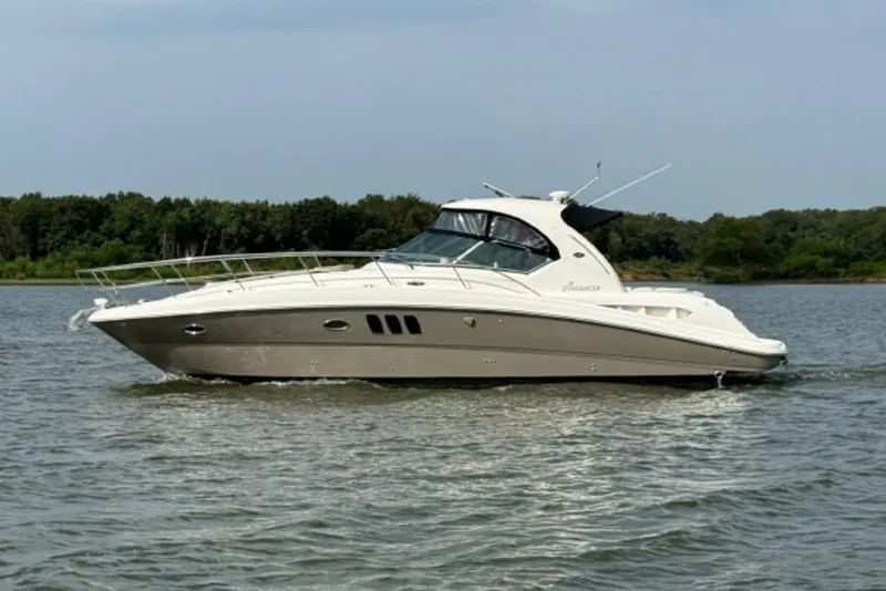 The Image of 2006 Sea Ray 38 Sundancer yacht cruising on a calm lake with forested shoreline. - 0